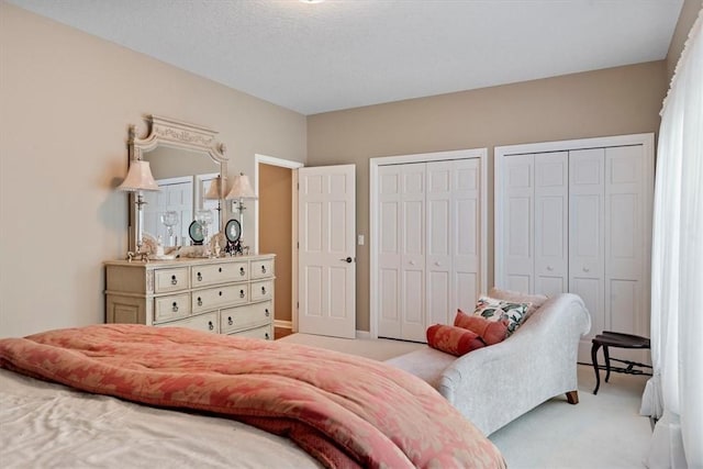 bedroom featuring two closets and light colored carpet