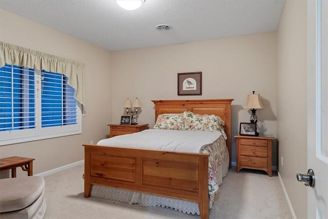 bedroom featuring light colored carpet and a textured ceiling