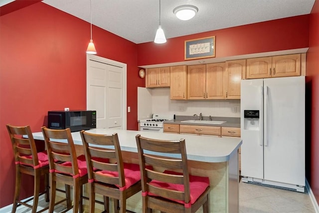 kitchen featuring white appliances, a textured ceiling, decorative light fixtures, sink, and a breakfast bar