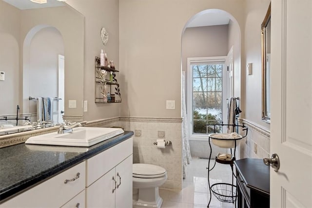 bathroom featuring toilet, a wealth of natural light, tile walls, and vanity