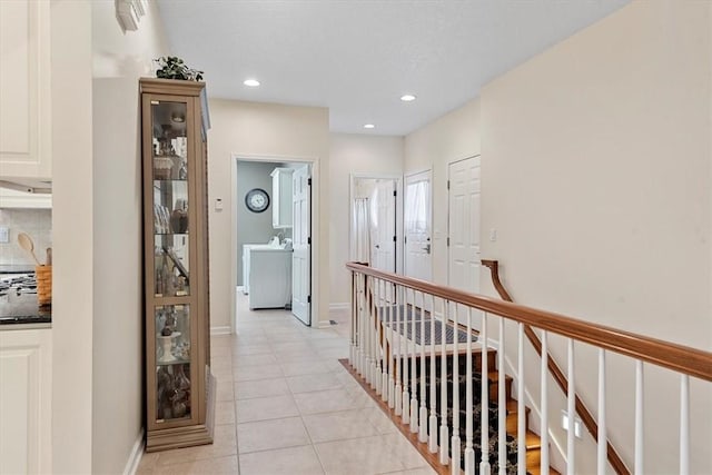 corridor with light tile patterned floors and washer / dryer