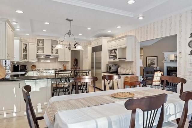 tiled dining space with sink, a tray ceiling, and ornamental molding