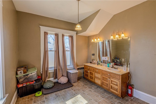 bathroom with vaulted ceiling, double vanity, baseboards, and a sink