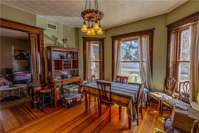 dining space featuring a notable chandelier, visible vents, and hardwood / wood-style flooring