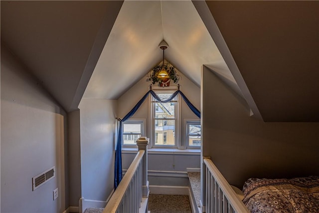 interior space featuring visible vents, baseboards, carpet flooring, and vaulted ceiling