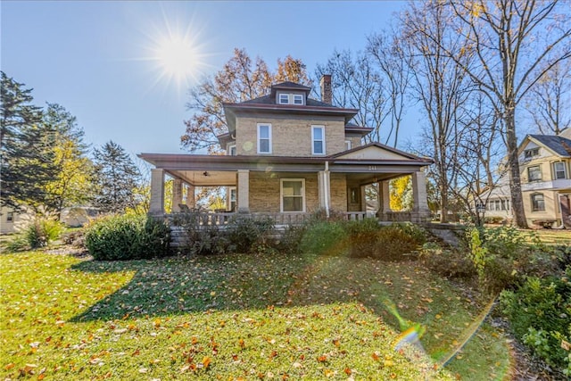 view of front of house featuring a porch, a front lawn, and a chimney