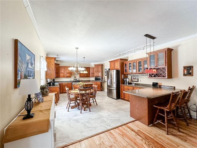 1165 Crooked Ln, Dennison, IL 62423 - kitchen with a peninsula, crown molding, brown cabinets, a breakfast bar area, and appliances with stainless steel finishes