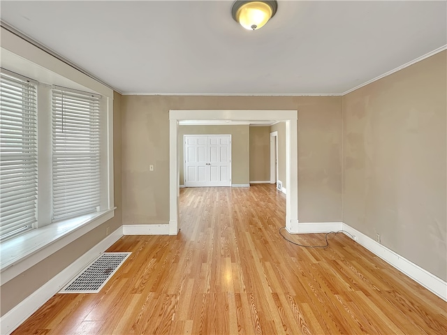 unfurnished room with light wood-type flooring and crown molding