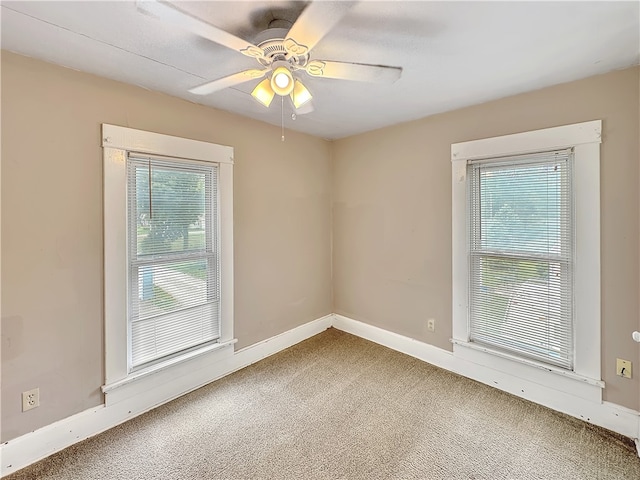 carpeted spare room with ceiling fan and plenty of natural light