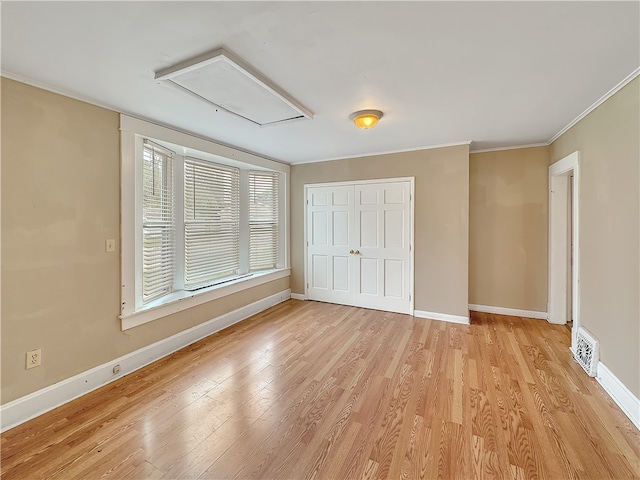 unfurnished bedroom featuring light wood-type flooring, crown molding, and a closet
