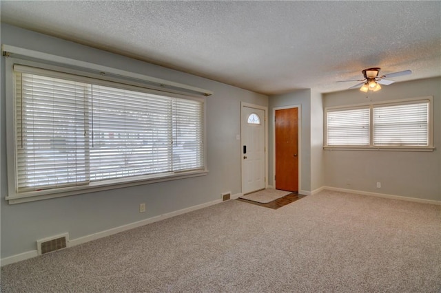 carpeted entryway featuring ceiling fan and a textured ceiling