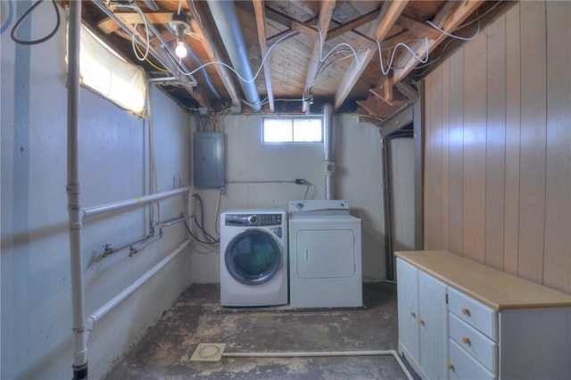 laundry area featuring washing machine and dryer, electric panel, and wood walls