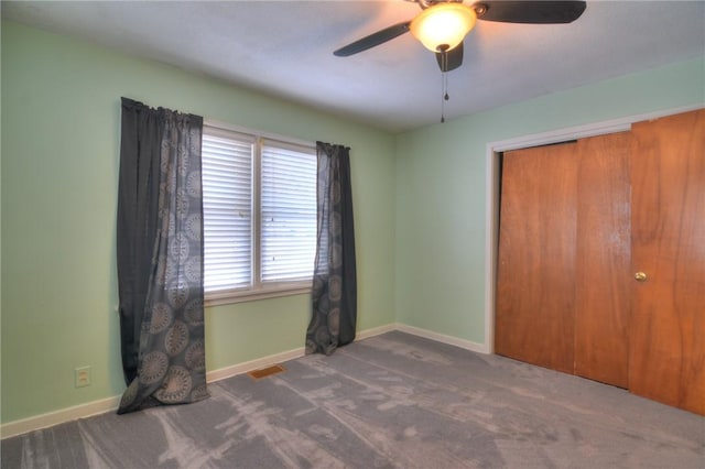 unfurnished bedroom featuring ceiling fan, a closet, and dark colored carpet