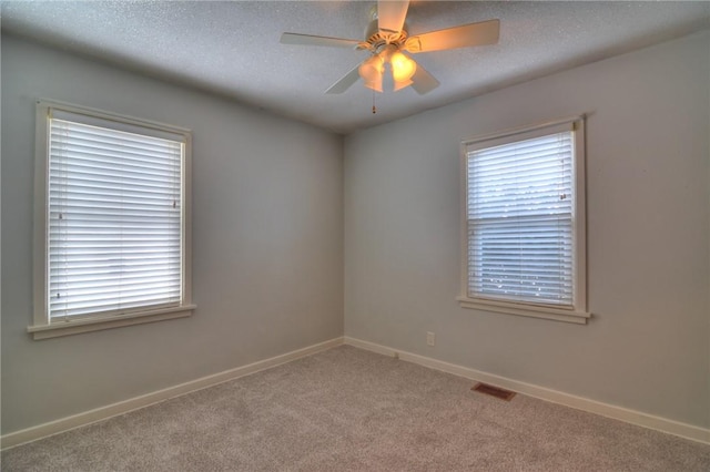 spare room featuring ceiling fan, light carpet, and a textured ceiling