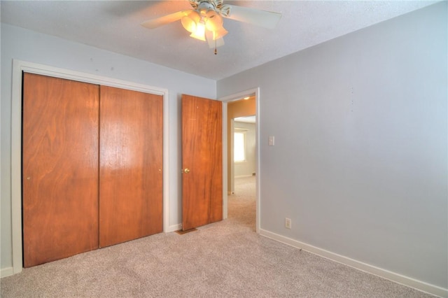 unfurnished bedroom with ceiling fan, light carpet, and a closet