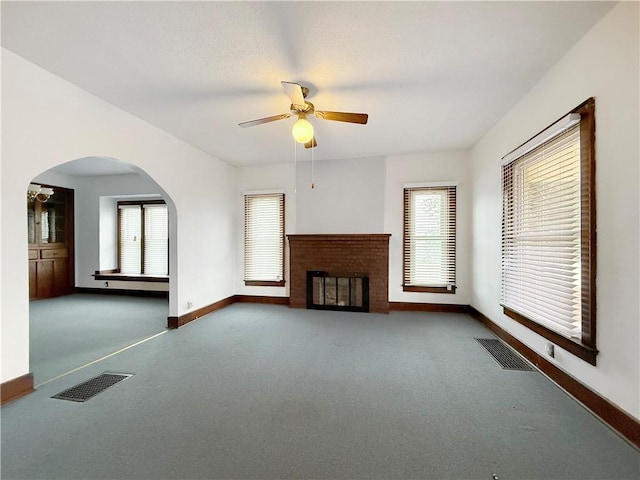 111 Andrew St, Paris, IL 61944 - unfurnished living room with carpet, ceiling fan, a brick fireplace, and arched walkways