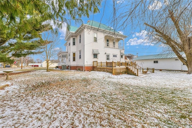 rear view of house featuring central AC unit and a balcony