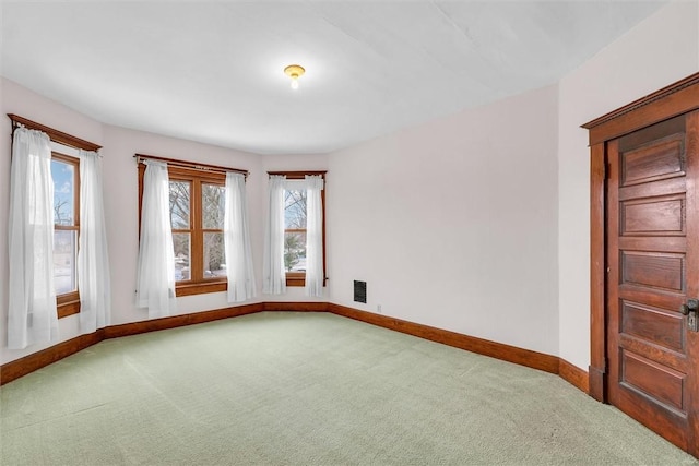 empty room with carpet floors, visible vents, and baseboards