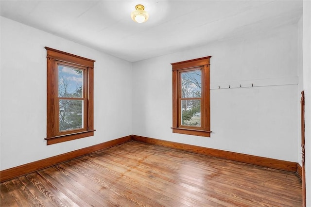 spare room with a healthy amount of sunlight, baseboards, and wood finished floors