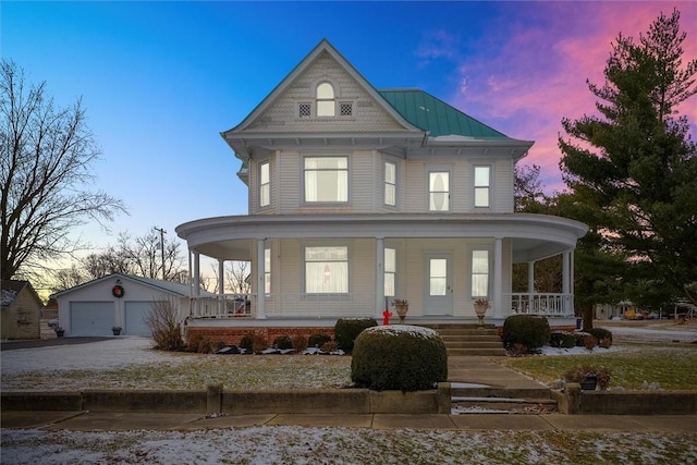 victorian house featuring an outbuilding, metal roof, a porch, and a detached garage