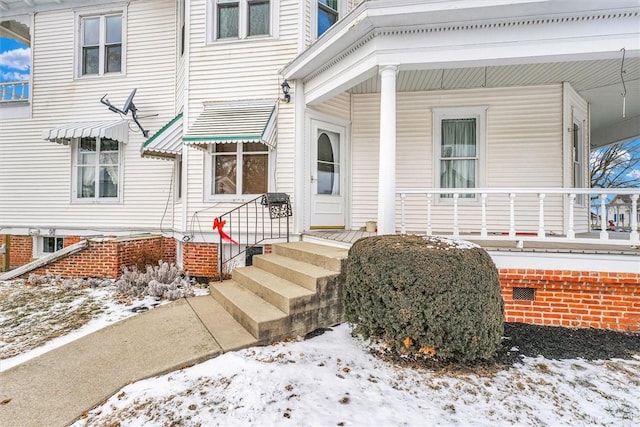 snow covered property entrance with covered porch