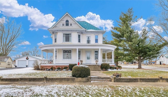 victorian home featuring an outbuilding, a detached garage, a porch, a standing seam roof, and metal roof