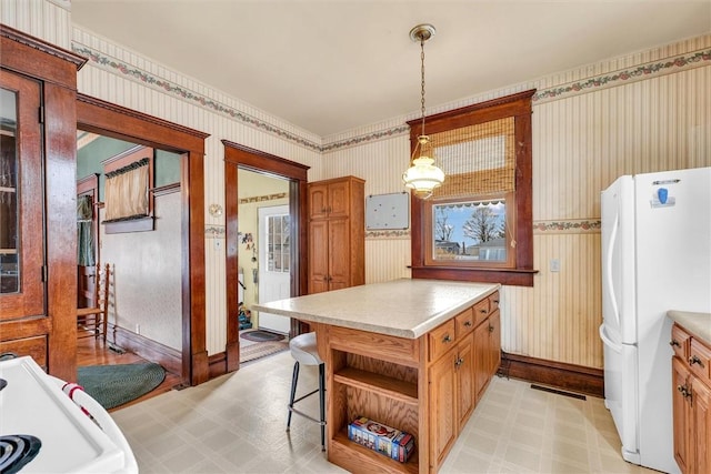 kitchen with wallpapered walls, freestanding refrigerator, light countertops, light floors, and open shelves