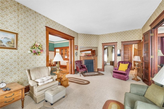 carpeted living area featuring wallpapered walls, a fireplace, and baseboards