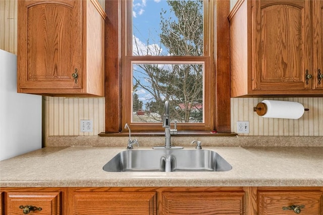 kitchen featuring brown cabinets, light countertops, and a sink