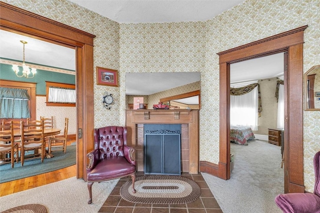 sitting room featuring wallpapered walls, a fireplace, baseboards, and an inviting chandelier