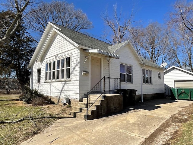 view of front of property with concrete driveway and a shingled roof