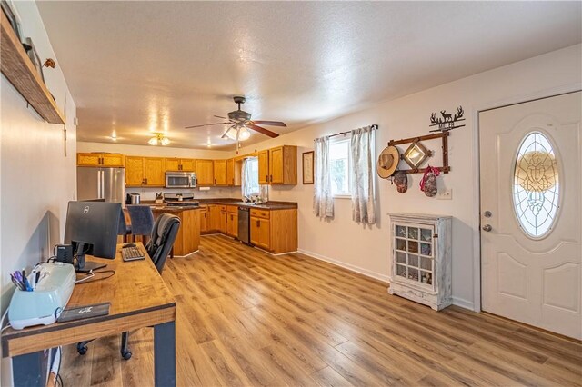 2430 Baker Ln, Decatur, IL 62526 - kitchen with appliances with stainless steel finishes, light wood finished floors, brown cabinets, a ceiling fan, and dark countertops