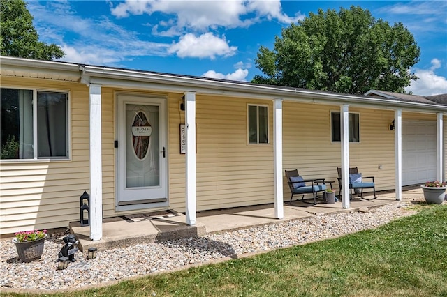 2430 Baker Ln, Decatur, IL 62526 - view of exterior entry featuring a porch and an attached garage