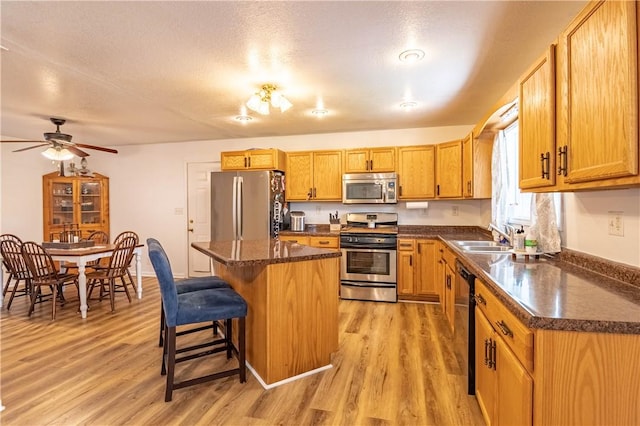 2430 Baker Ln, Decatur, IL 62526 - kitchen featuring appliances with stainless steel finishes, a center island, light wood-style flooring, a breakfast bar, and ceiling fan