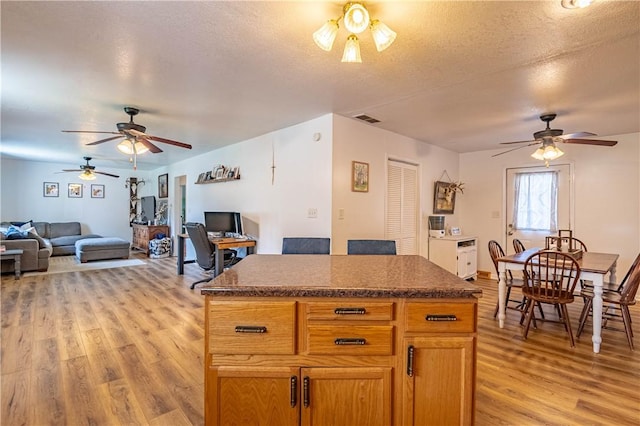 2430 Baker Ln, Decatur, IL 62526 - kitchen featuring a ceiling fan, open floor plan, light wood-style flooring, a center island, and a textured ceiling