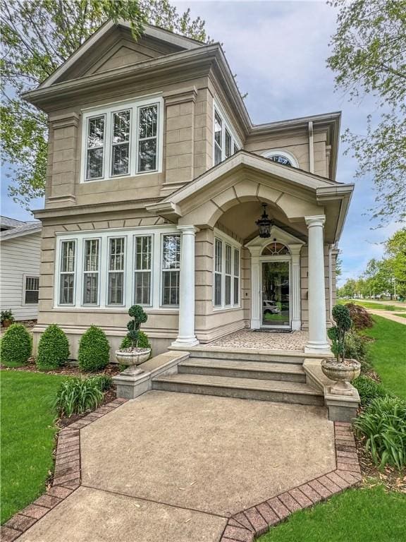 view of exterior entry with a lawn and a porch