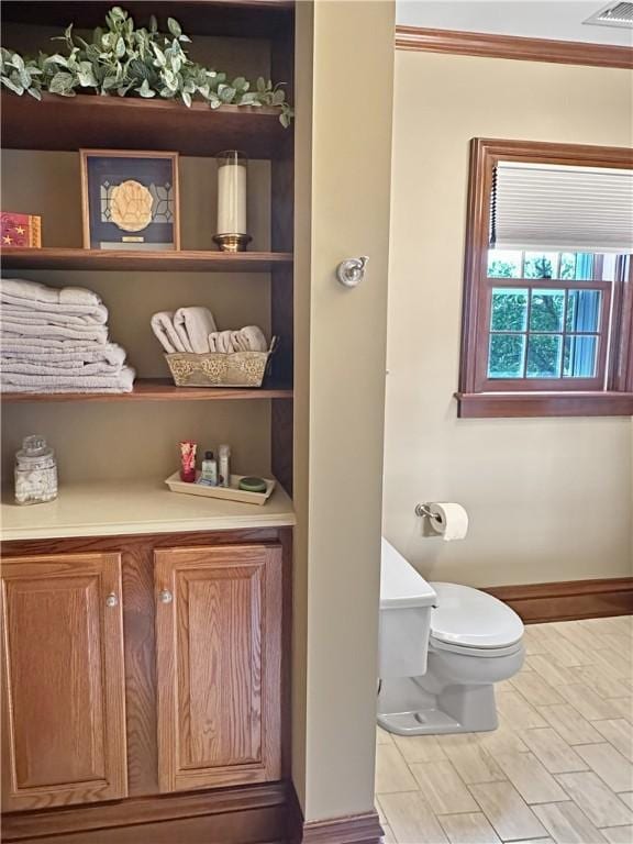 bathroom featuring toilet, baseboards, and crown molding