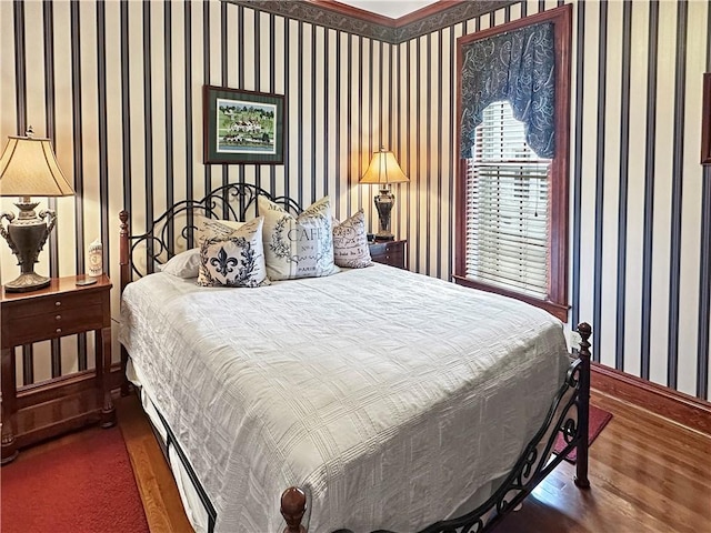 bedroom featuring wallpapered walls, wood finished floors, and baseboards
