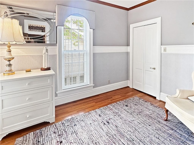 sitting room featuring wood finished floors, a wainscoted wall, ornamental molding, and baseboards