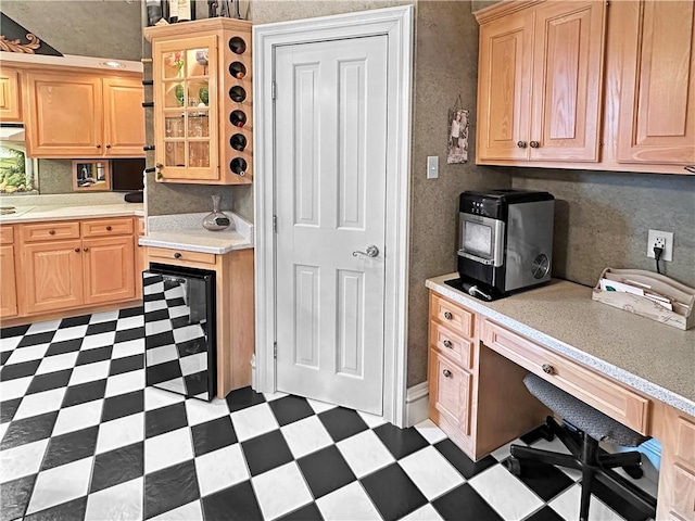 kitchen featuring light floors, light countertops, light brown cabinetry, and beverage cooler