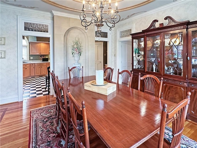 dining space featuring light wood-type flooring, a chandelier, ornamental molding, and baseboards