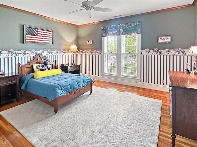 bedroom with wood finished floors, crown molding, and a ceiling fan