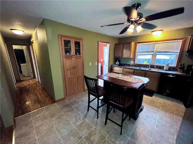 kitchen featuring a textured ceiling, ceiling fan, sink, black dishwasher, and light hardwood / wood-style floors