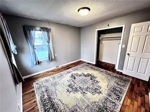 bedroom featuring a textured ceiling, a closet, and dark hardwood / wood-style floors