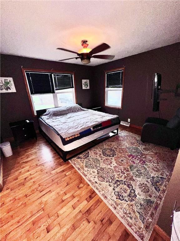 bedroom with hardwood / wood-style floors, a textured ceiling, and ceiling fan