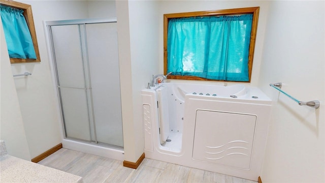 full bathroom with baseboards, a bath, wood finished floors, and a shower stall