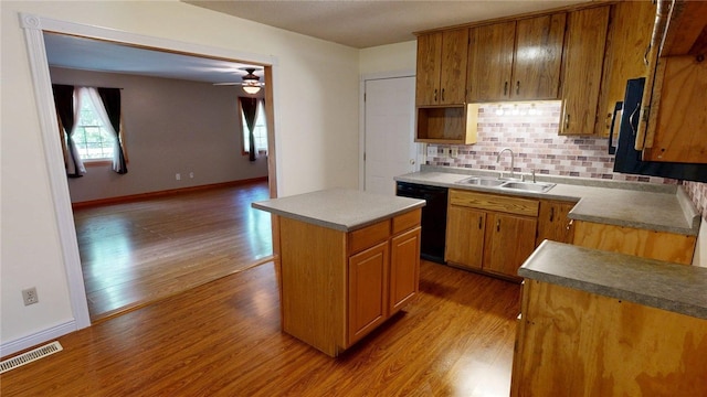kitchen with a sink, dishwasher, wood finished floors, tasteful backsplash, and visible vents