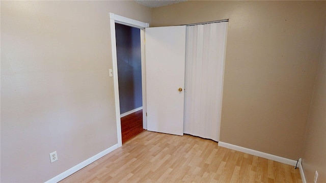 unfurnished bedroom featuring baseboards, a closet, and light wood finished floors