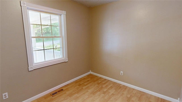spare room featuring baseboards, visible vents, and light wood finished floors
