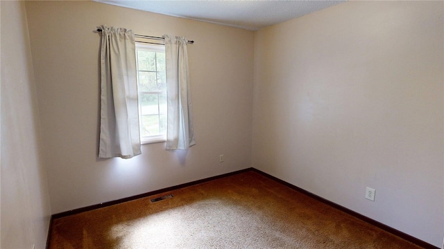 unfurnished room with visible vents, baseboards, and dark carpet